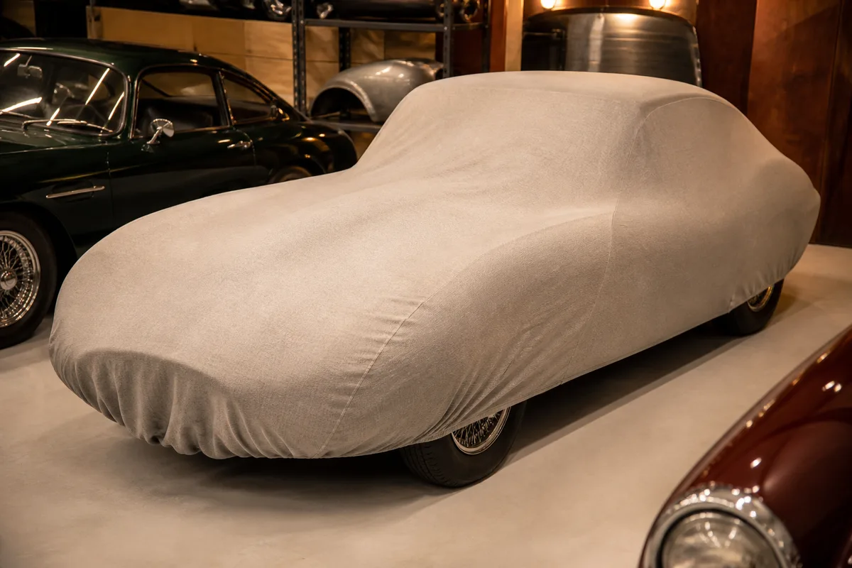 Voiture de collection stockée sous une housse respirante dans un garage sec